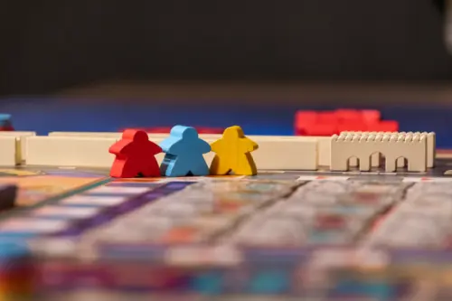 SPIEL Essen 2026: Neuheiten, Tickets, Termine & die besten Tipps 4 Fotorealistische Nahaufnahme farbiger Meeple und Brettspiel-Komponenten